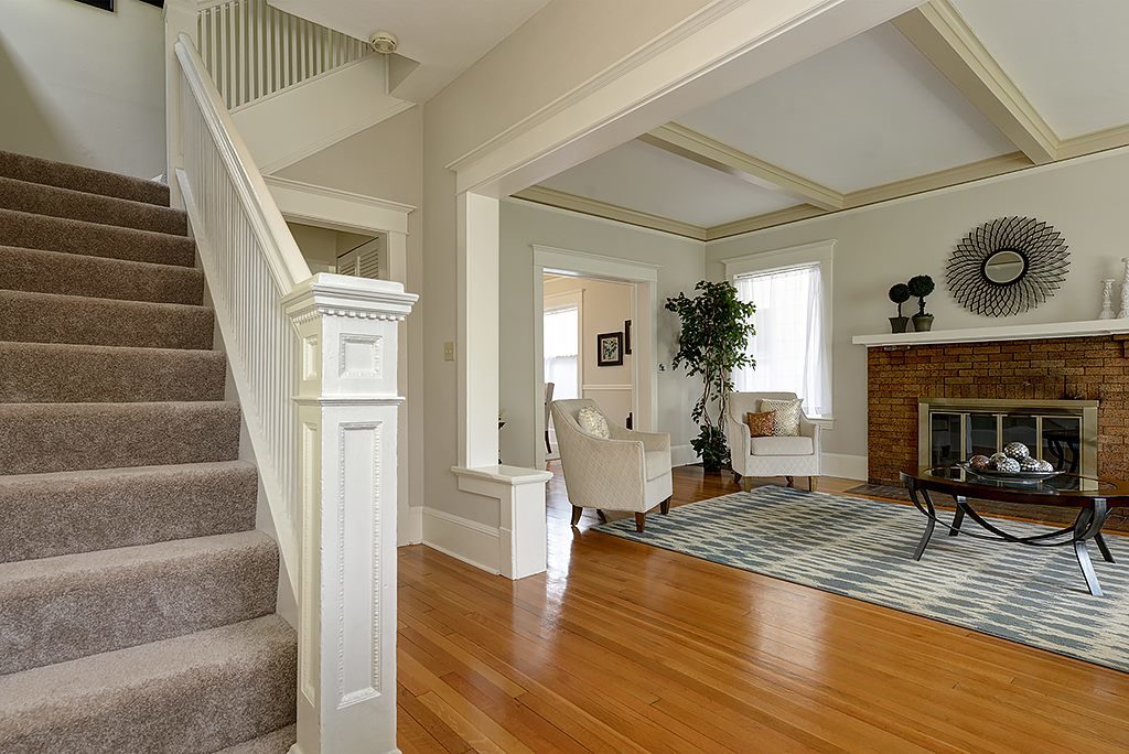 residential stairway bottom wooden railing molding white fireplace chairs windows wood beam ceiling