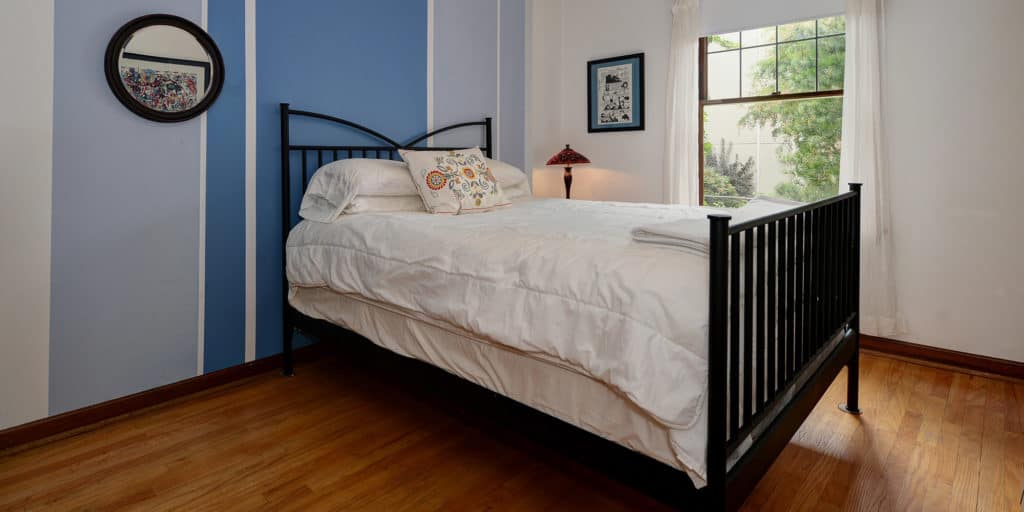 bedroom small bed window curtains blue accent wall hardwood floors